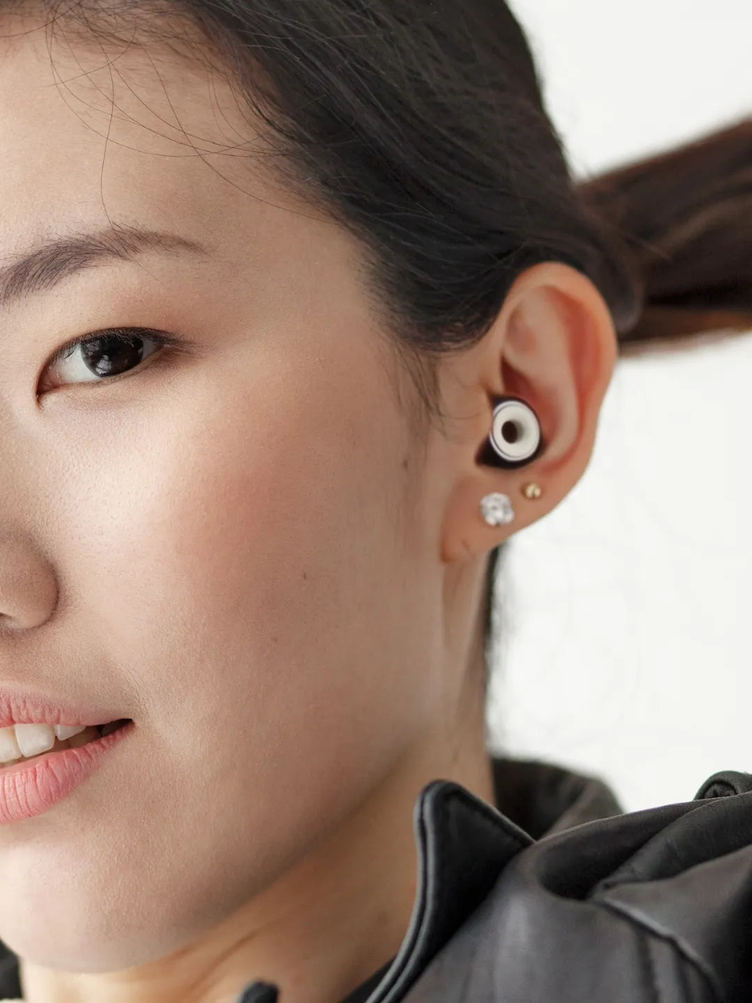 Close-up of a person wearing an earplug against a white blurred background | Altitude Philippines