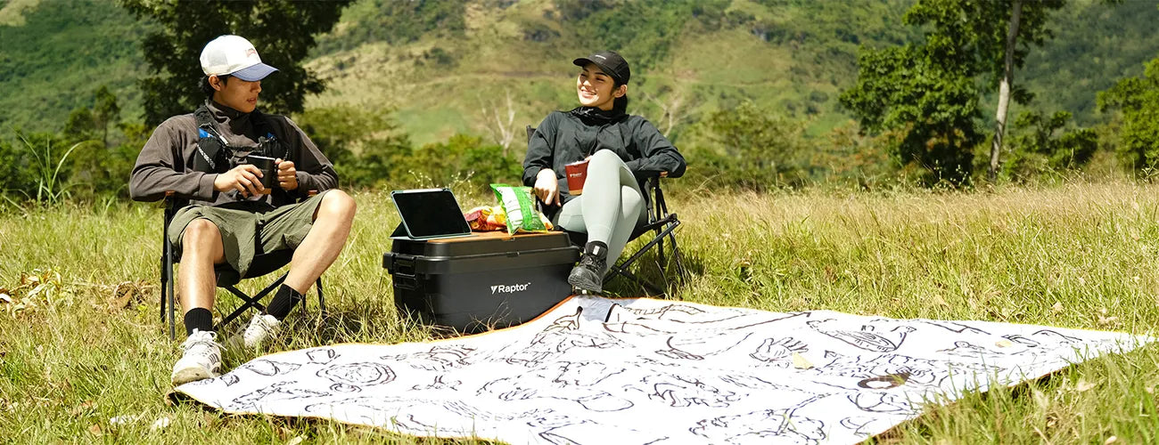 Two people enjoying a picnic on a grassy field with a hard case and travel mug | Altitude Philippines