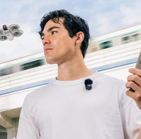 DJI Mic Mini Transmitter on a shirt with a DJI drone flying overhead
