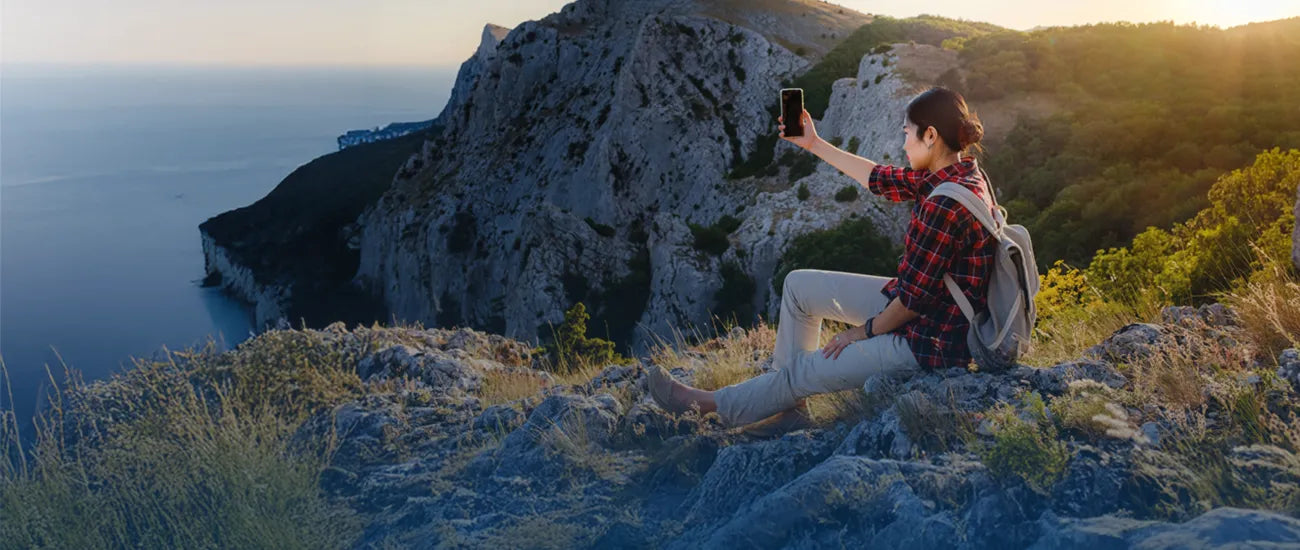 Woman taking photos on a seaside mountain with scenic ocean views and warm sunlight | Altitude Philippines