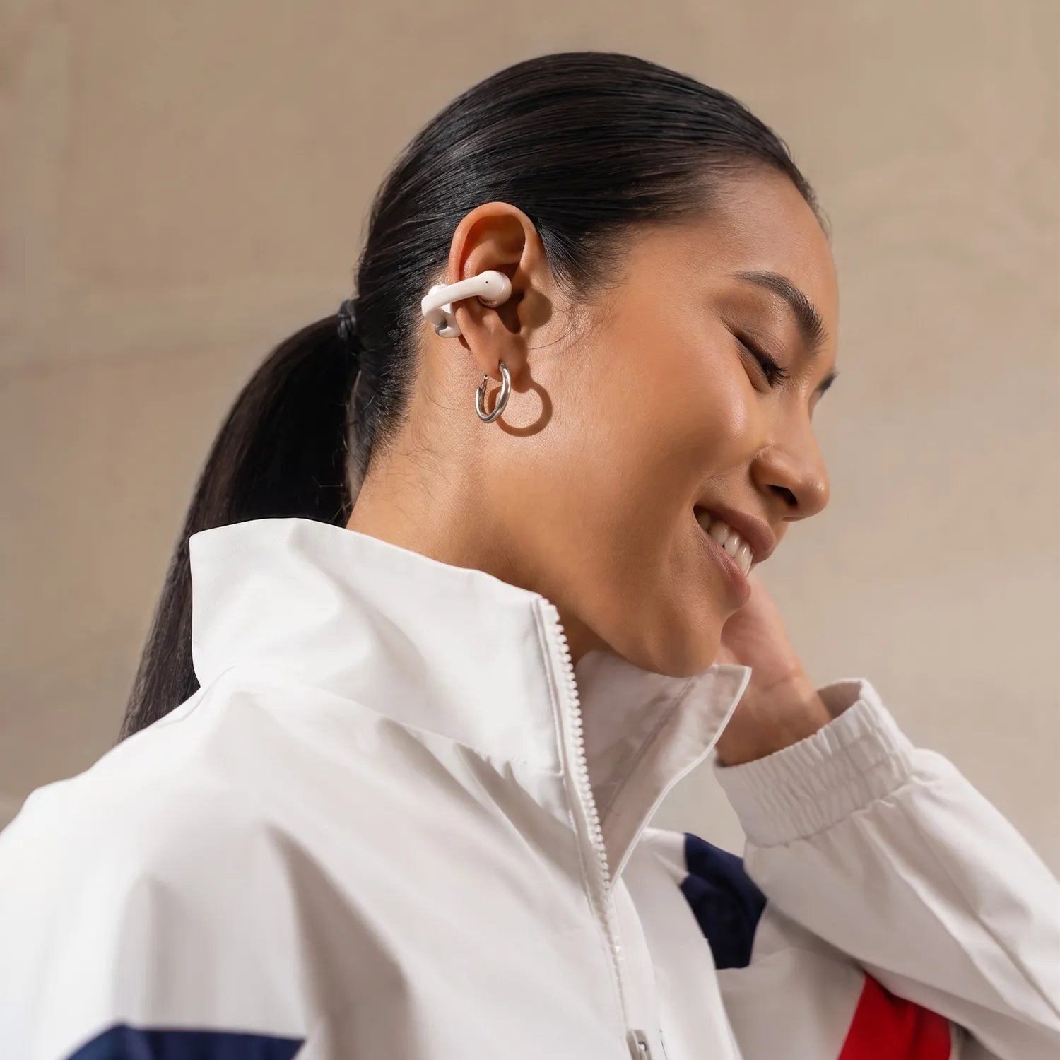 Woman listening using earplugs, wearing a white jacket, smiling | Altitude Philippines