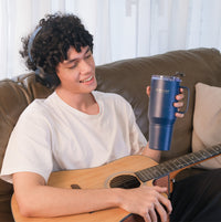 man drinking from the Raptor Drinkware Fusion 28 oz while holding the guitar
