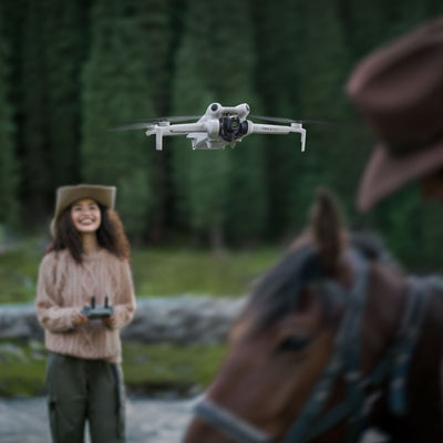 DJI Mini 4 Pro being flown using a remote by a woman